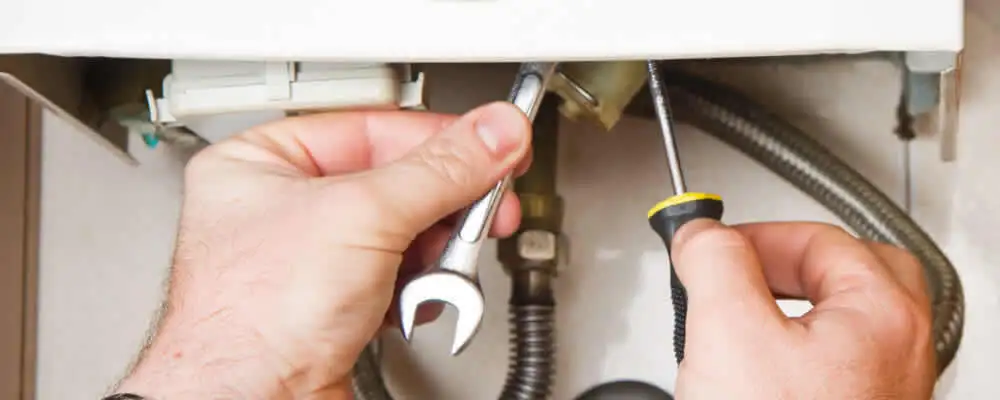 Boiler repair technician tightening pipe fittings and connections in Dallas, TX