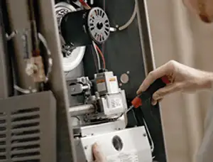 Furnace repair technician inspecting internal components and wiring in Dallas, TX