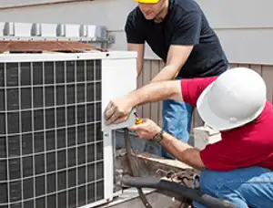 HVAC technicians repairing an outdoor AC unit on a rooftop in Dallas, TX