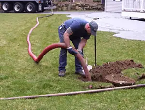 Septic pumping technician servicing a residential septic tank with a vacuum hose in Dallas, TX