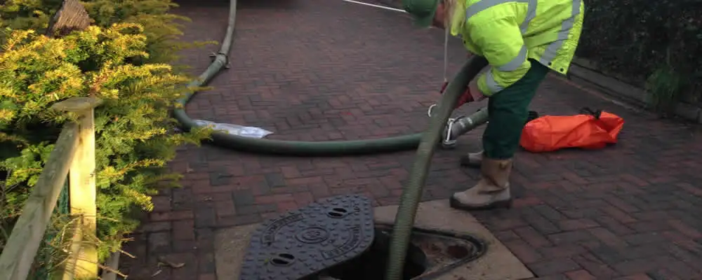 Septic tank cleaning technician servicing a septic tank with a vacuum hose in Dallas, TX