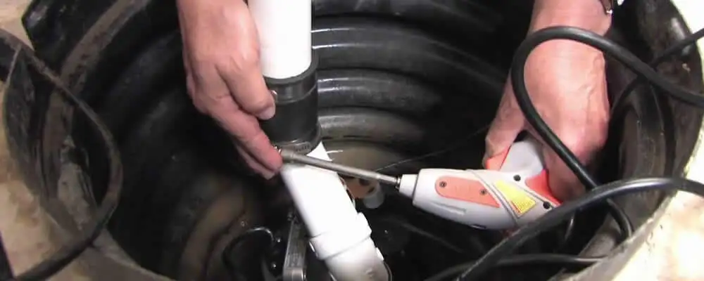 Sump pump installation technician connecting PVC discharge piping in Dallas, TX