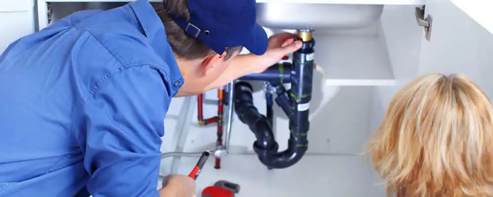 Plumber repairing under-sink drain pipes and fittings in Dallas, TX